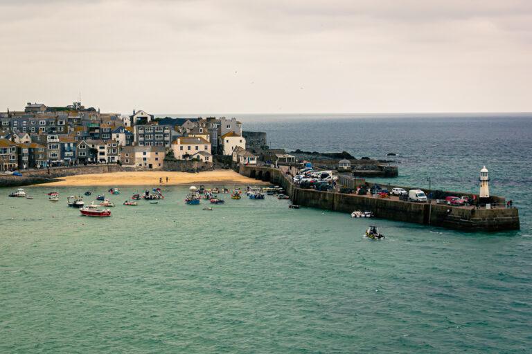 Small fishing boats in a sheltered harbour beside a coastal town and sea wall